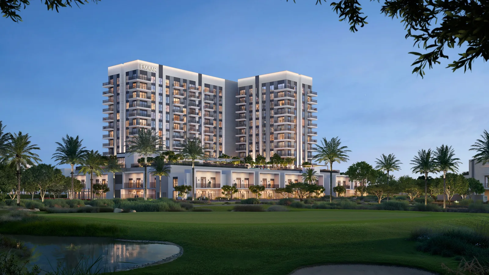 Dusk exterior render of the Golf Fields residential building and townhouses overlooking the fairway, Emaar South